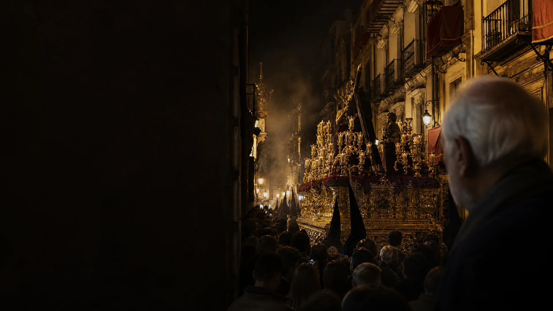 Procesión nocturna en una calle histórica de Andalucía